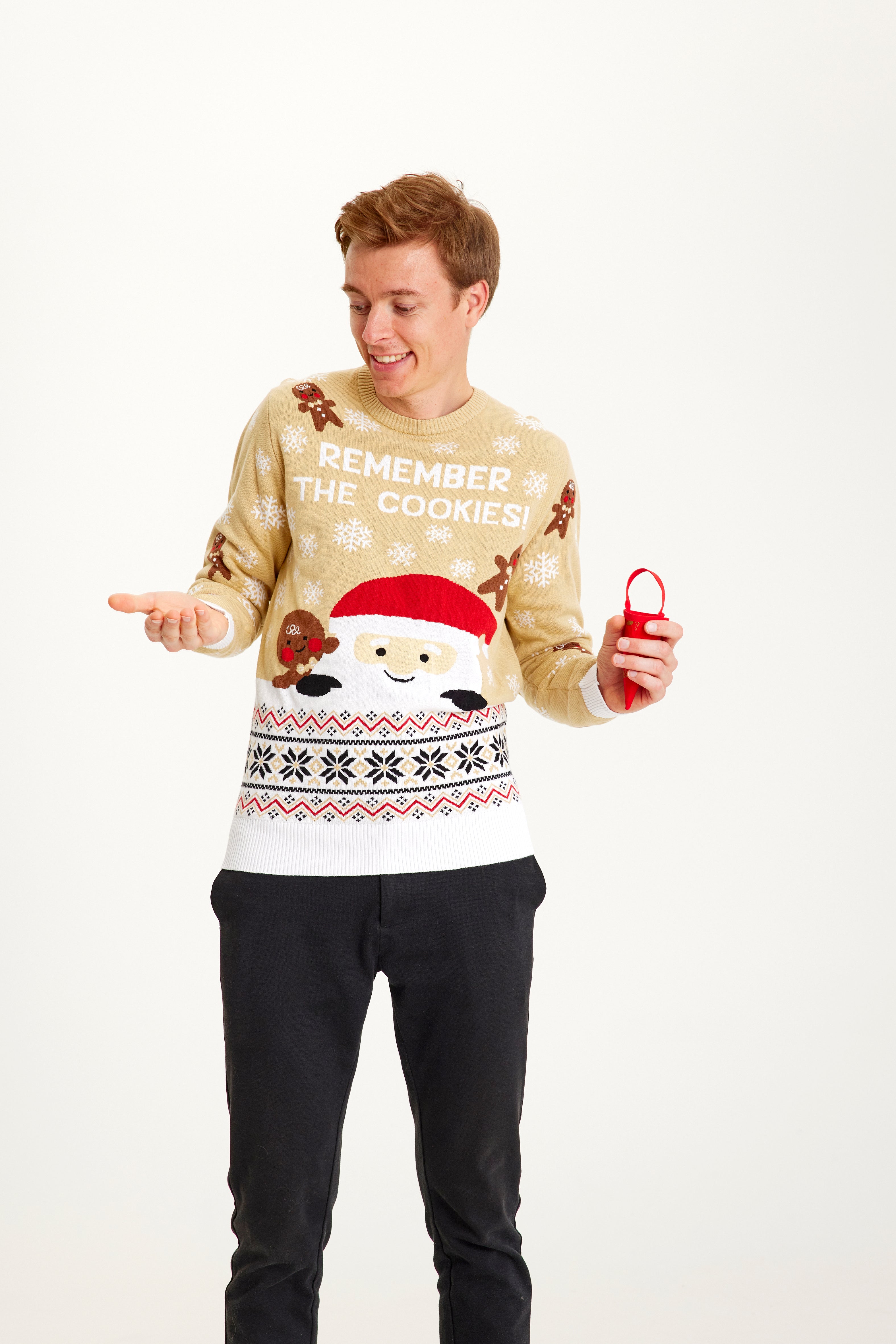 Ein Mann posiert in einem beigen Weihnachtspulli mit dem Spruch